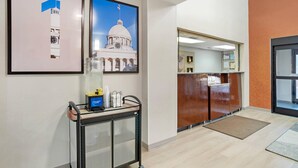A reception area with a cart, framed pictures, and a wooden reception desk. - Comfort Inn Livingston (Livingston)