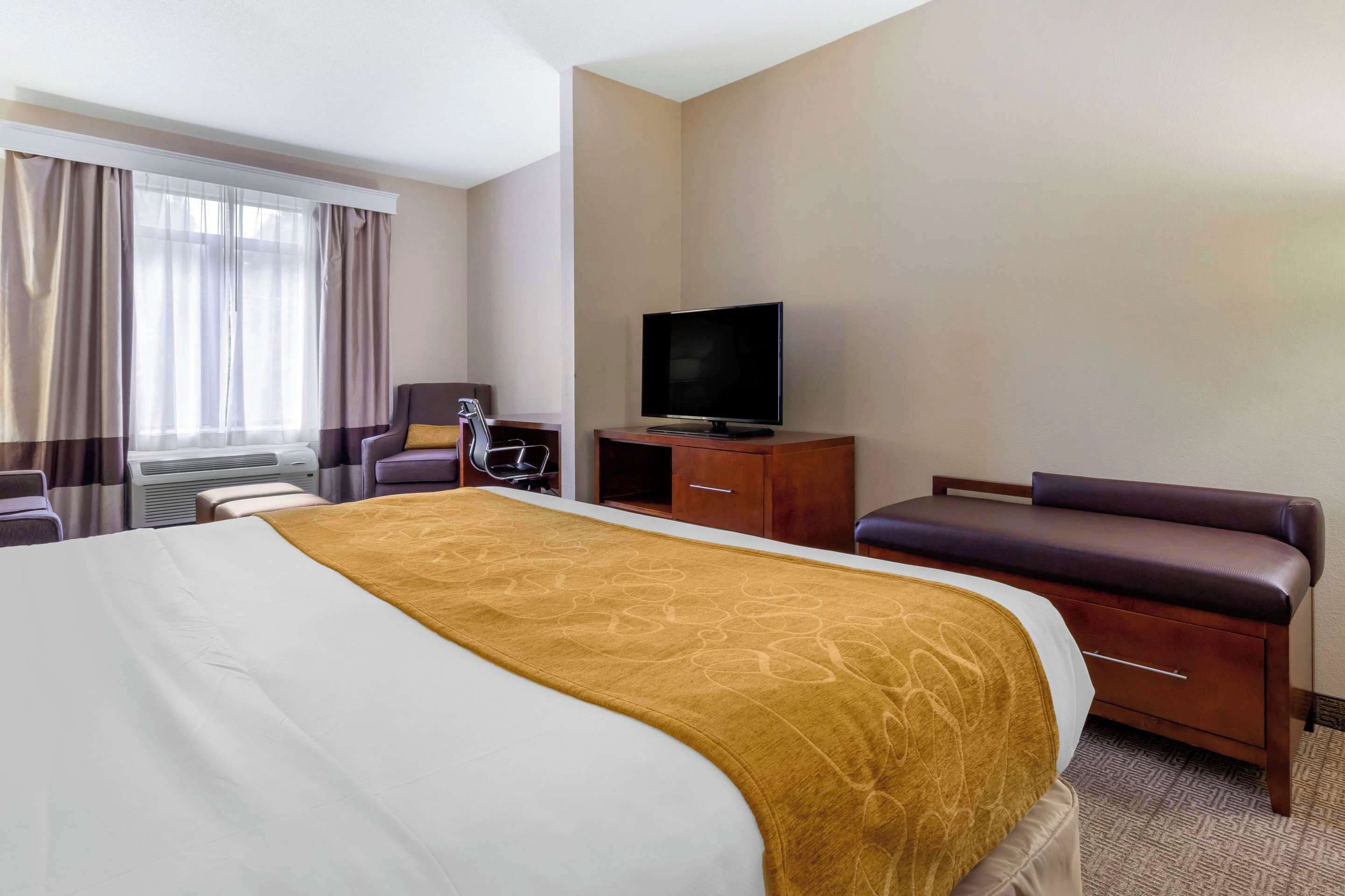 A hotel room with a large bed, a television, a desk, and a seating area.