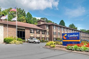 Un hotel Comfort Suites con fachada de ladrillo, varias ventanas y un estacionamiento.