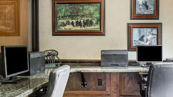 Escritório moderno com uma mesa grande, dois monitores, uma impressora e quadros com temas da vida selvagem na parede.