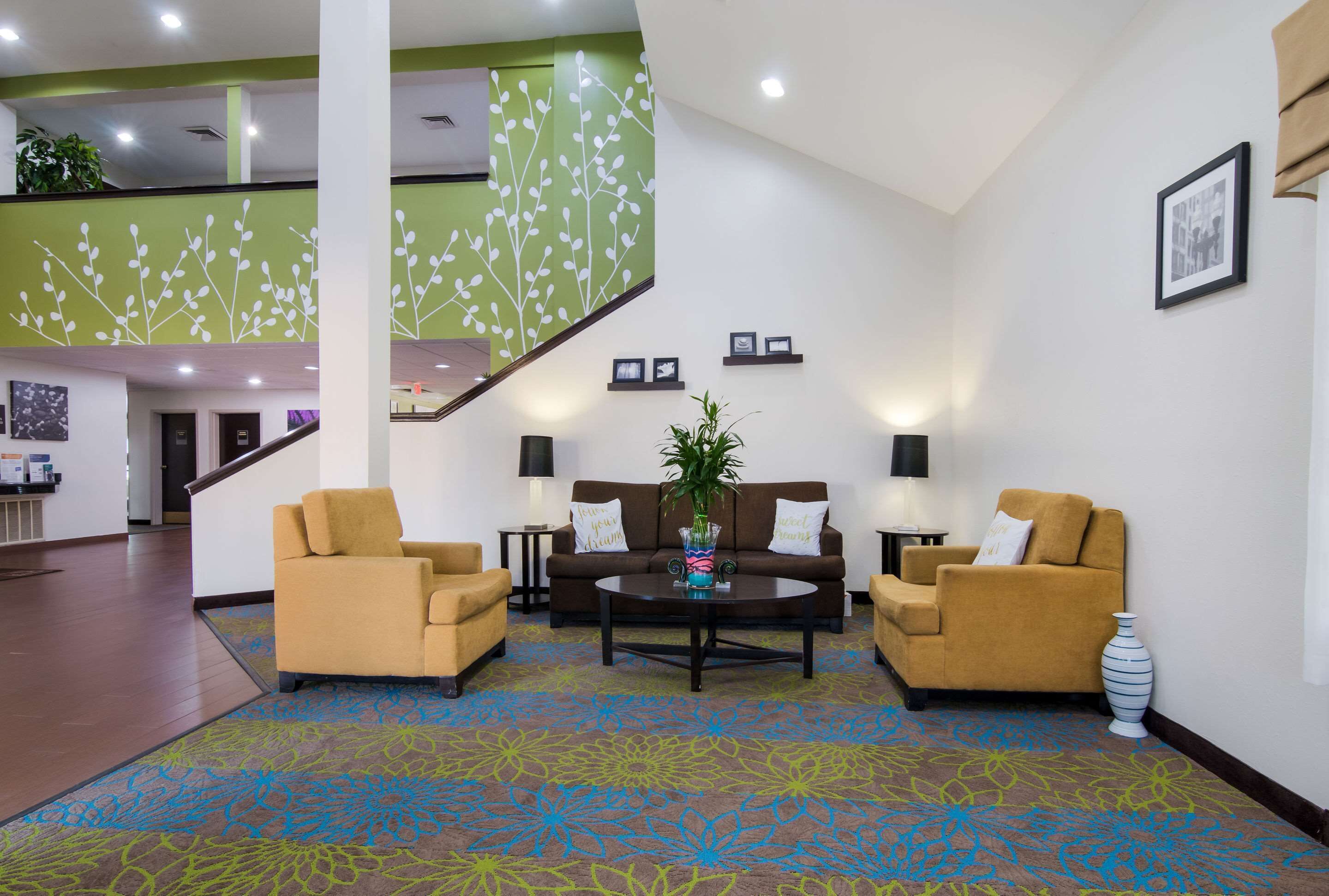 A lobby with a staircase, two sofas, a coffee table, and a vase with plants.