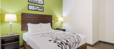 A hotel room with a bed, two bedside lamps, a nightstand, and two framed pictures on the wall.