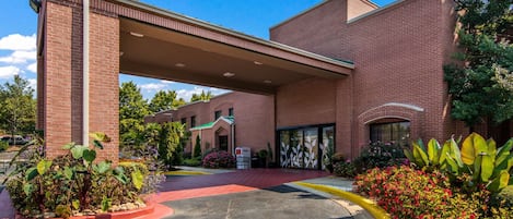 A brick building with a covered entrance and a landscaped driveway.