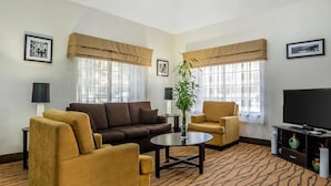 A living room with a brown sofa, yellow armchairs, a coffee table, and a television.