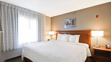 Een hotelkamer met een groot bed, twee bedlampen, een nachtkastje en een lijst aan de muur.