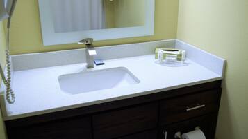 Un baño con un lavabo blanco, un espejo, un perchero para toallas y un porta papel higiénico.