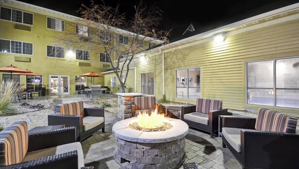 Un patio con mesas al aire libre, una chimenea y un edificio con amplias ventanas.