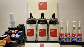 Eine Selbstbedienungs-Kaffeestation mit mehreren Spendern, beschriftet mit „Corner Cup“ und Torani-Aromasirupen.
