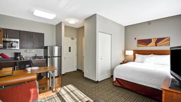 Habitación de hotel con cama, escritorio, kitchenette y baño.