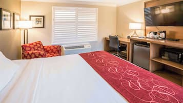 A hotel room with a bed, a desk, a television, and a microwave.