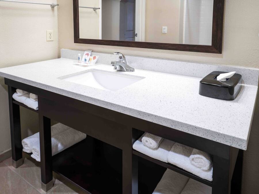 Un baño con lavamanos blanco, tocador de madera oscura y un perchero para toallas.