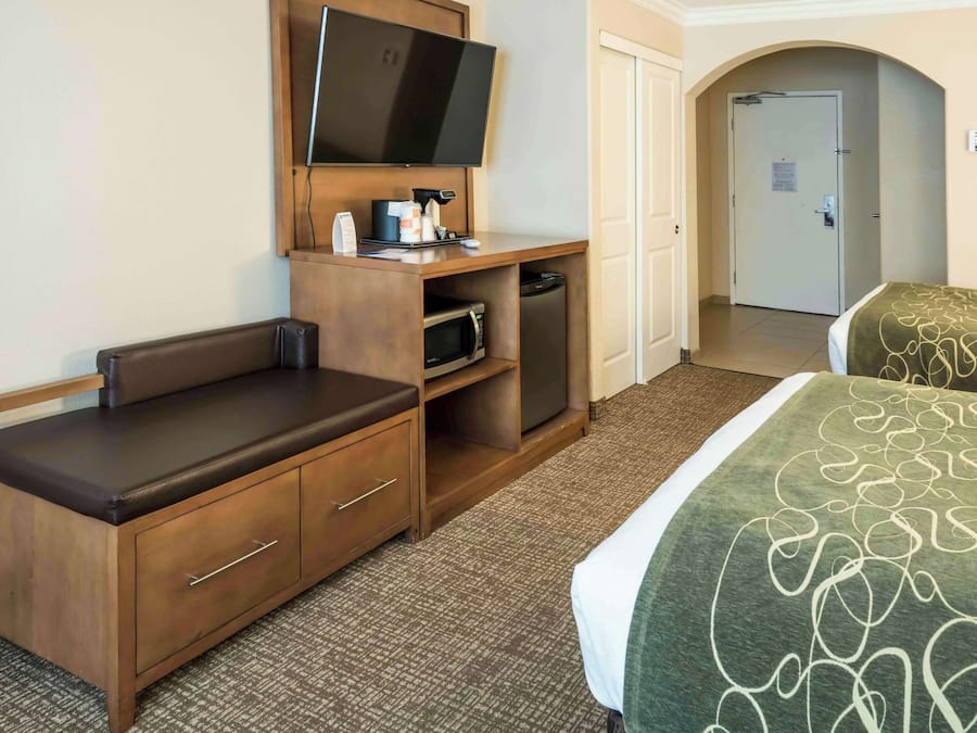 Quarto de hotel com cama, escrivaninha, televisão de tela plana, micro-ondas e mini-geladeira.
