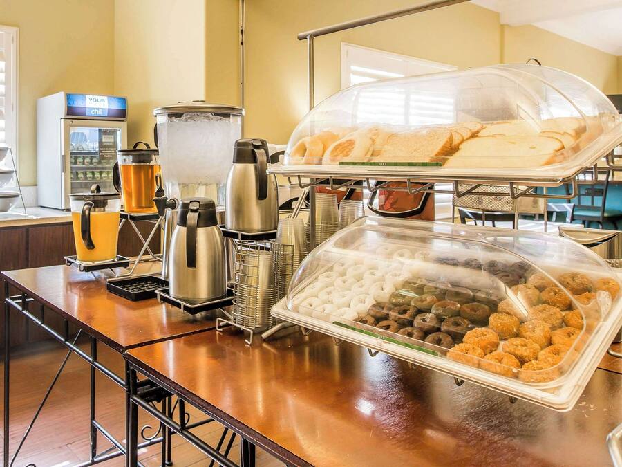 Dispositiu de buffet amb una màquina de cafè, un dosificador de begudes i diverses opcions gastronòmiques, incloent pastissos i mandonguilles.