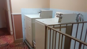 A laundry area with a washing machine, dryer, and a small cabinet. - Days Inn by Wyndham Pocatello University Area (Pocatello)