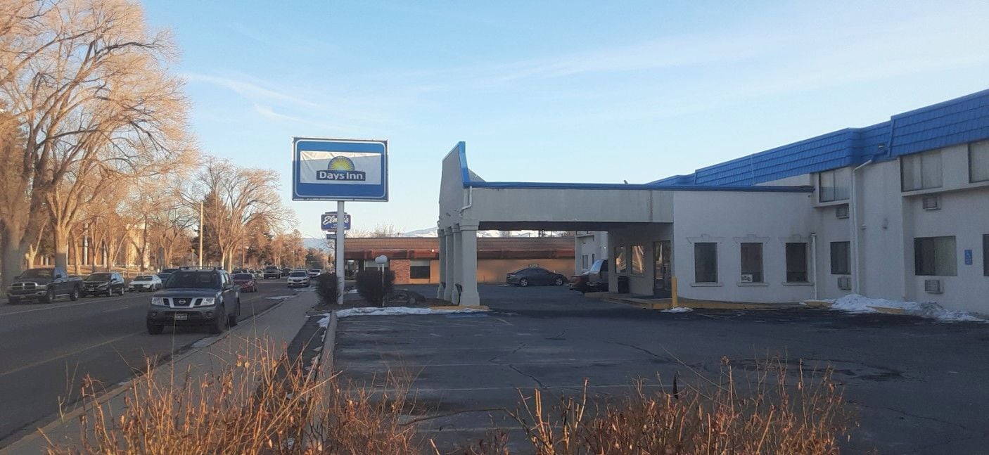 Un Days Inn con un estacionamiento, un edificio de techo azul y árboles desprovistos de hojas.