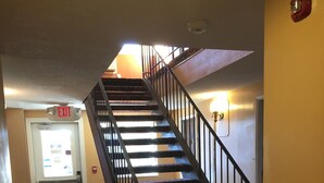 A carpeted staircase with a handrail, a fire alarm, and an exit sign. - Days Inn by Wyndham Pocatello University Area (Pocatello)
