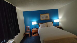 A hotel room with a bed, two bedside tables with lamps, a chair, and a painting on the wall. - Days Inn by Wyndham Pocatello University Area (Pocatello)