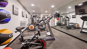 Un gimnasio con equipo de cardio, máquinas de pesas y pelotas de ejercicio.