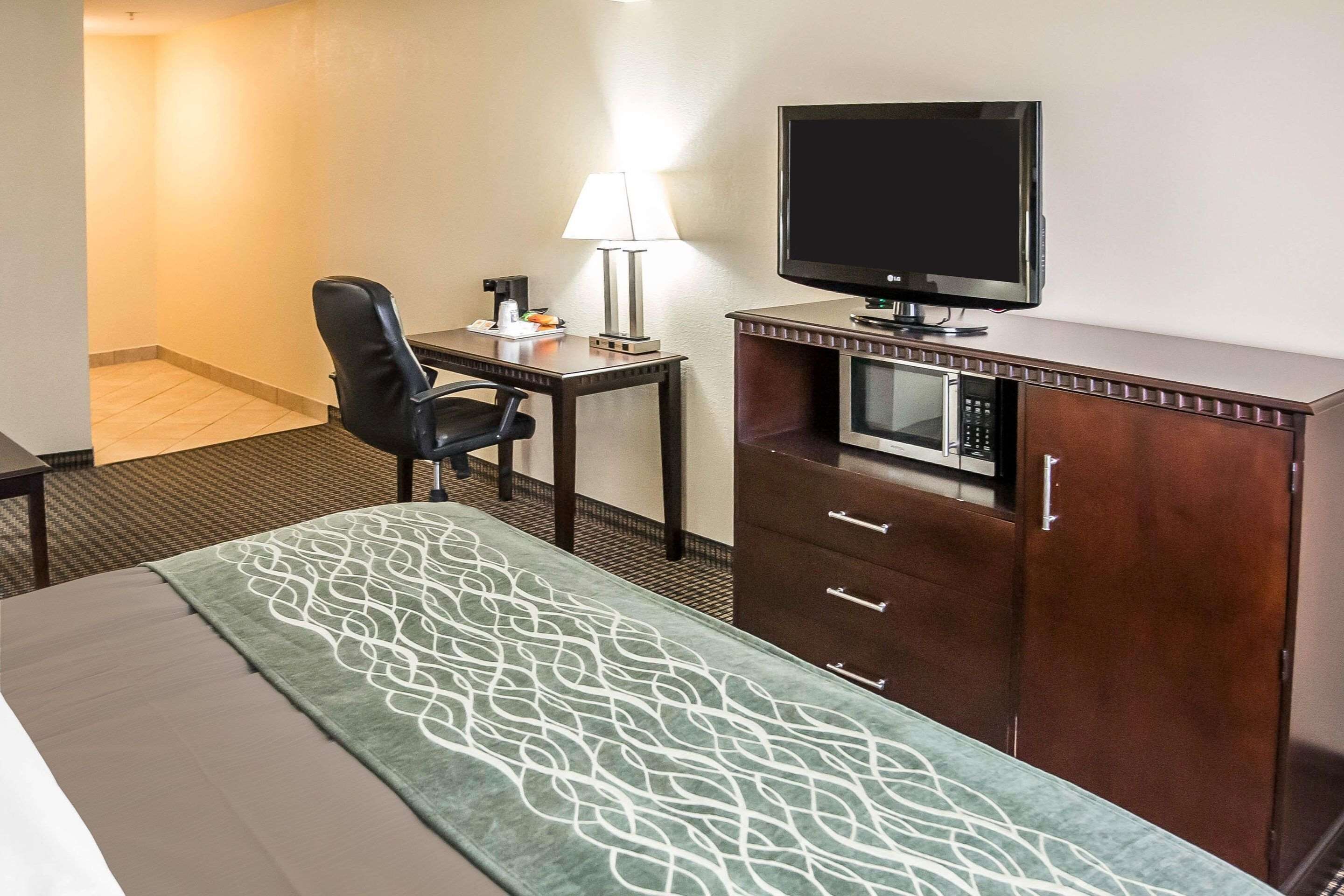 A hotel room with a bed, a desk with a lamp, a television, and a microwave.