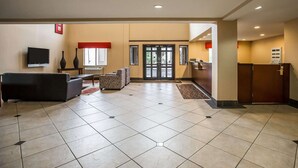 A lobby with a flat-screen TV, sofas, a reception desk, and a tiled floor.