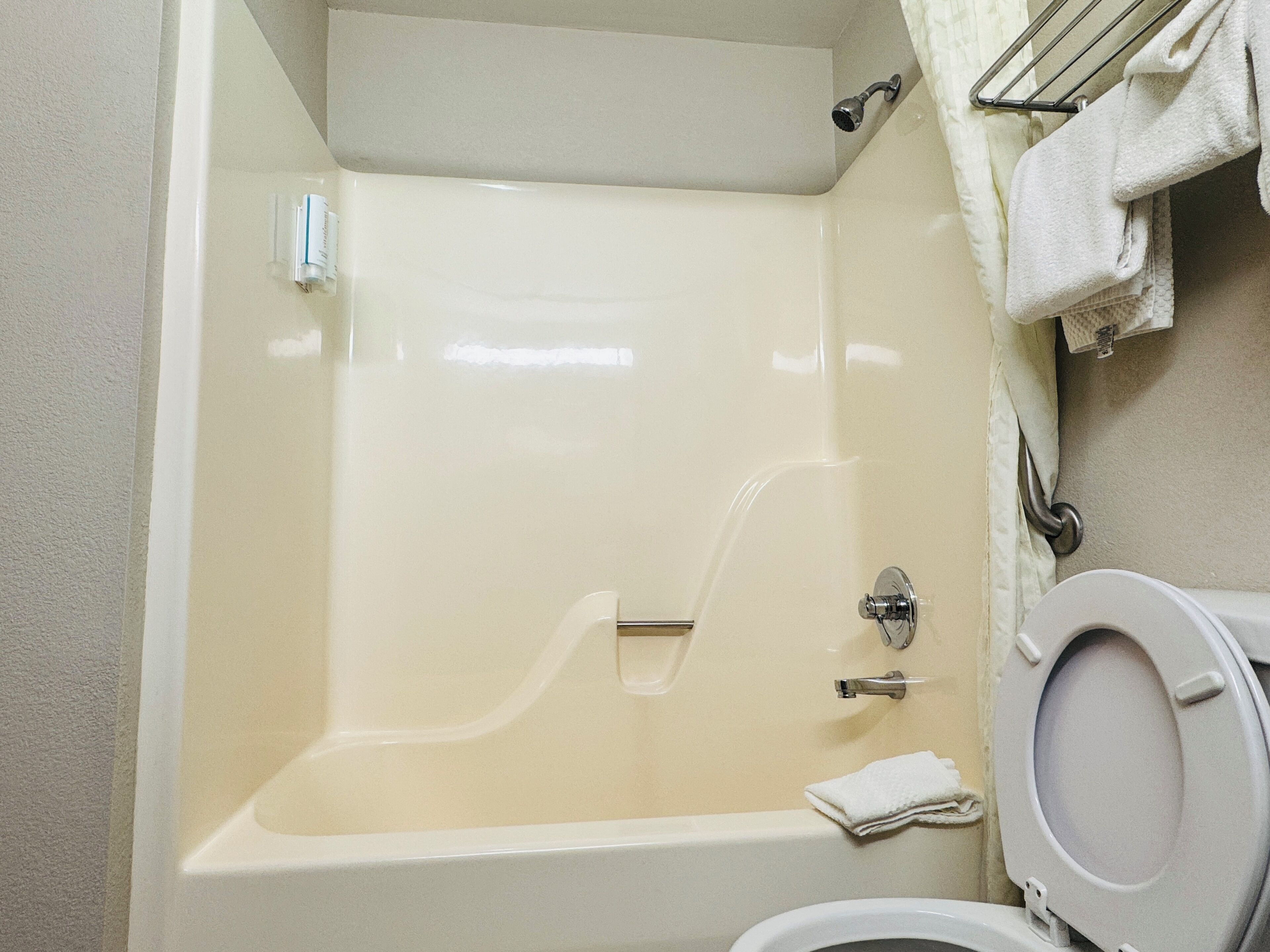 A bathroom with a bathtub, toilet, and a towel rack.