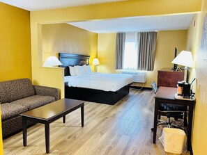 A hotel room with a bed, a sofa, a desk, and a chair.