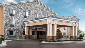 A hotel with a stone facade, a covered entrance, and a landscaped driveway.