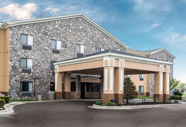 A hotel with a stone facade, a covered entrance, and a landscaped driveway.