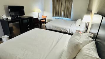 Habitación de hotel con dos camas, un escritorio con televisor, una silla y una ventana con cortinas.