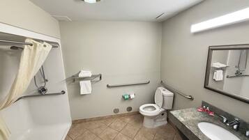 Un baño con inodoro, lavamanos, espejo, toallero y zona de ducha.