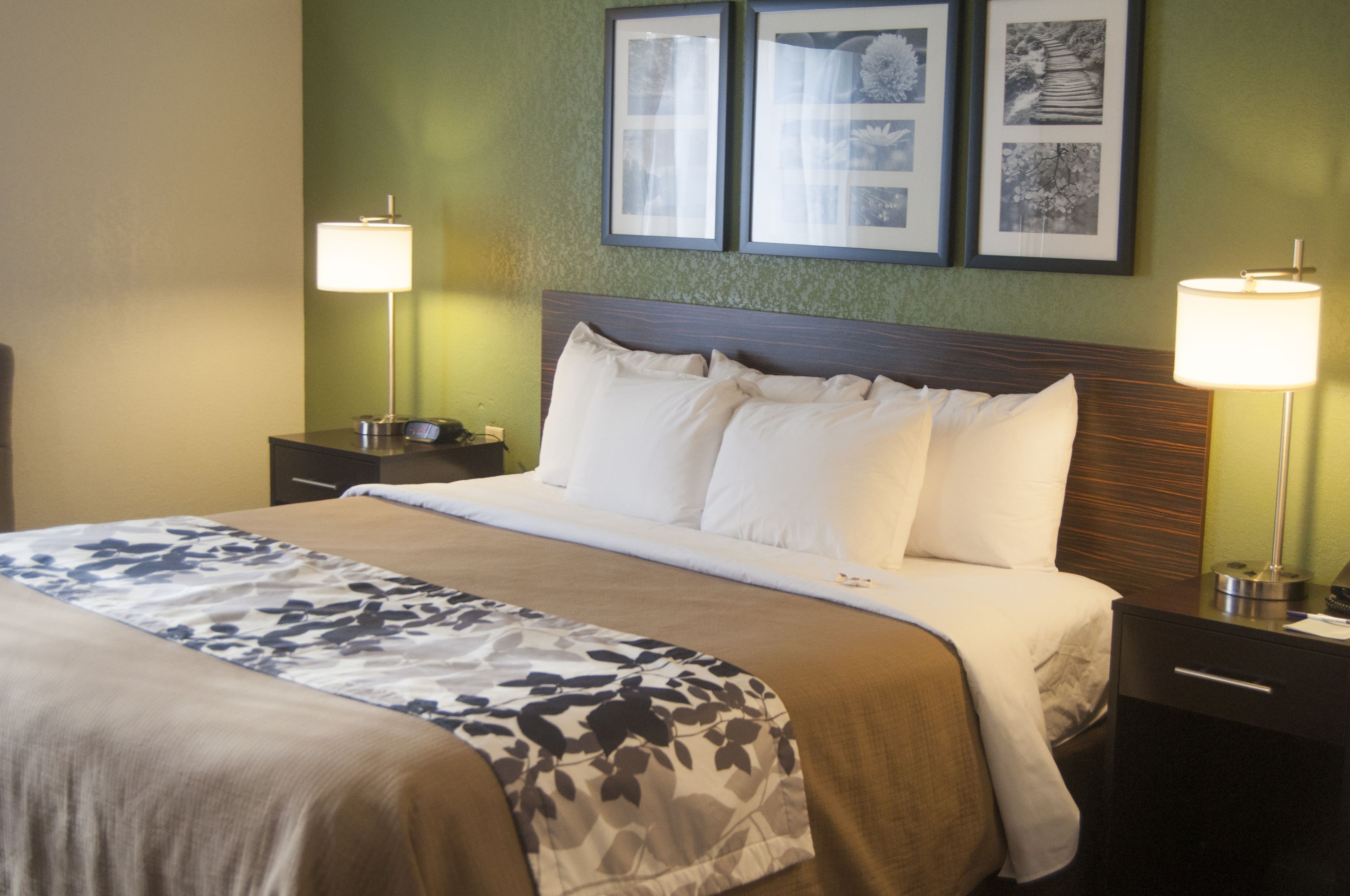 A neatly made bed with a floral bedspread, two bedside lamps, and framed pictures on the wall.