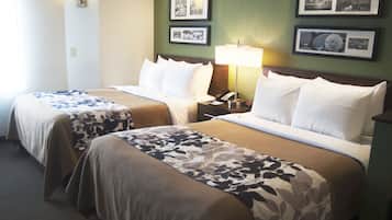 Una habitación de hotel con dos camas, una mesita de noche con lámpara y cuadros en la pared.