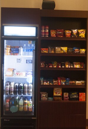 A vending machine stocked with beverages and snacks, including chips and cookies, in a wooden cabinet. - Sleep Inn & Suites Buffalo Airport (Buffalo)