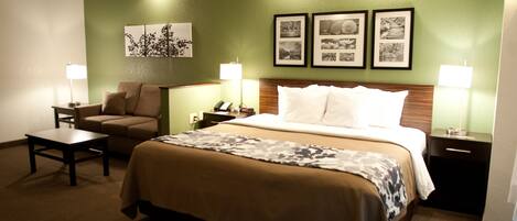 A hotel room with a bed, a chair, a nightstand, and a lamp.
