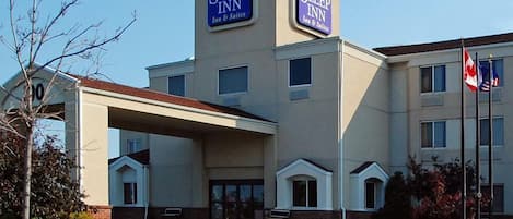 A Sleep Inn hotel with a central entrance, multiple windows, and a flagpole with flags.