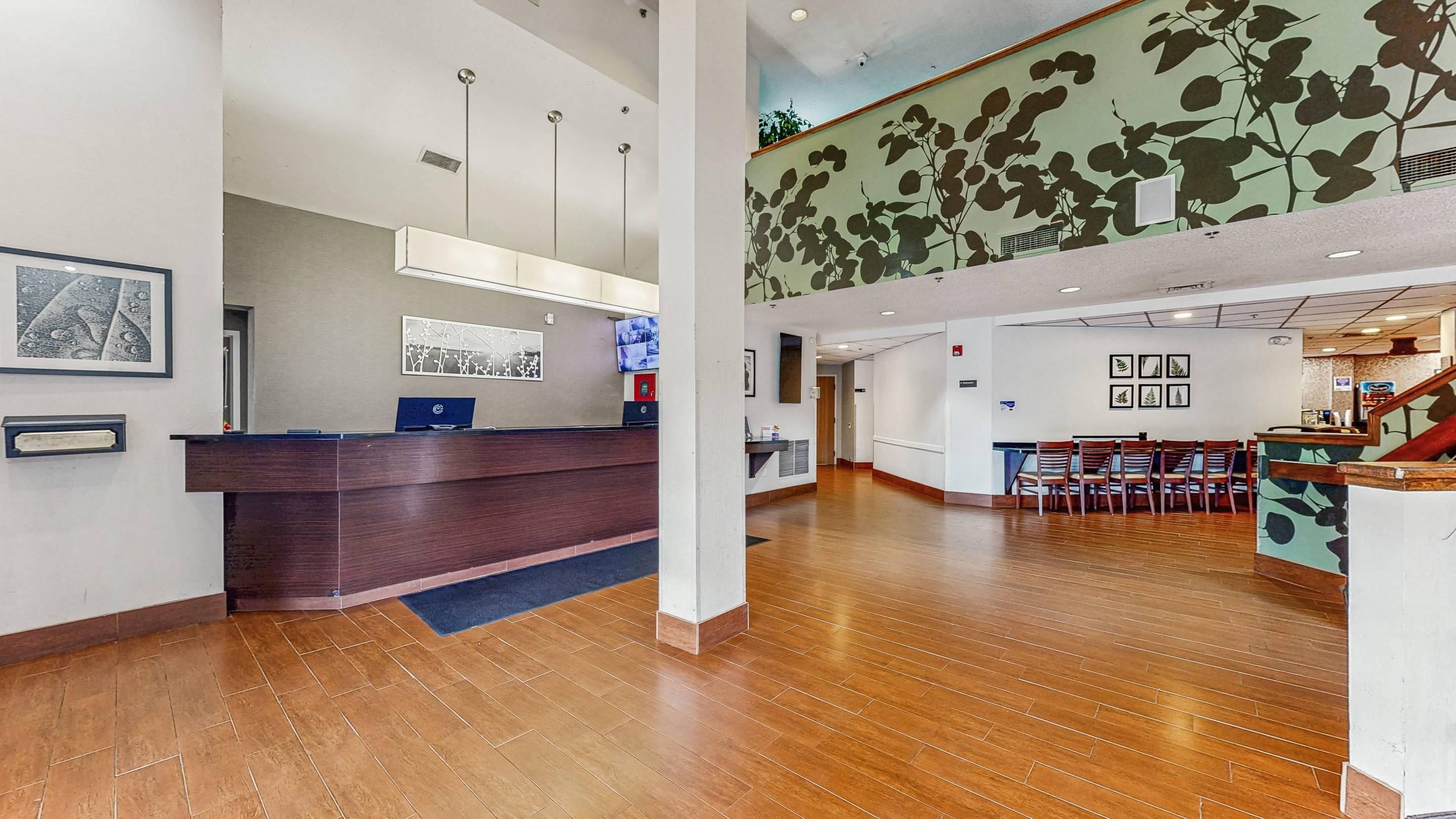 A reception area with a wooden reception desk, a flat-screen TV, and a seating area with chairs and a table.