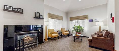 A hotel room with a fireplace, seating area, and a television.