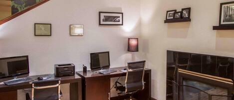 Un salón de conferencias con dos escritorios, sillas, una chimenea y cuadros en la pared.
