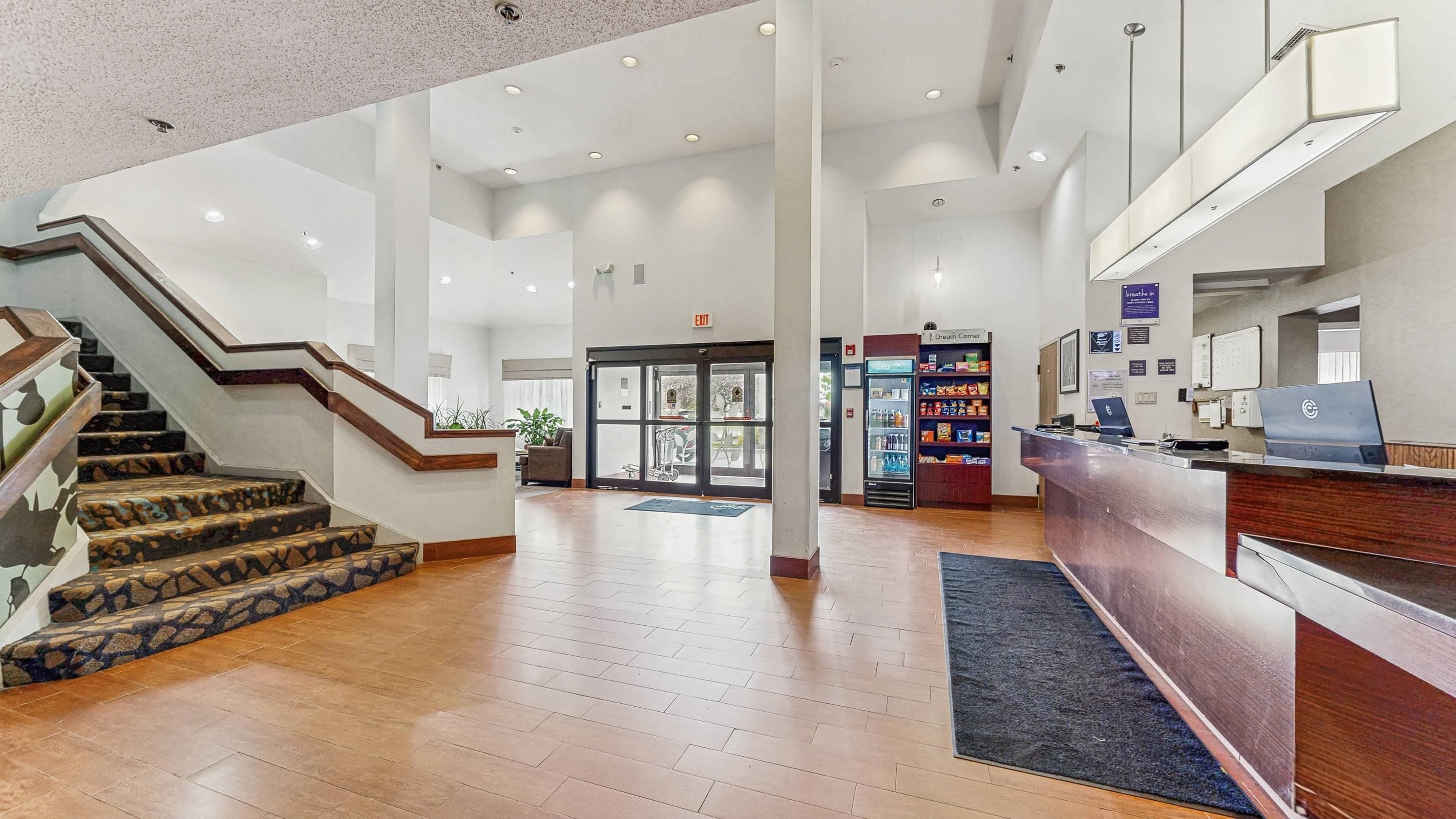 A hotel lobby with a staircase, a reception desk, and a vending machine.