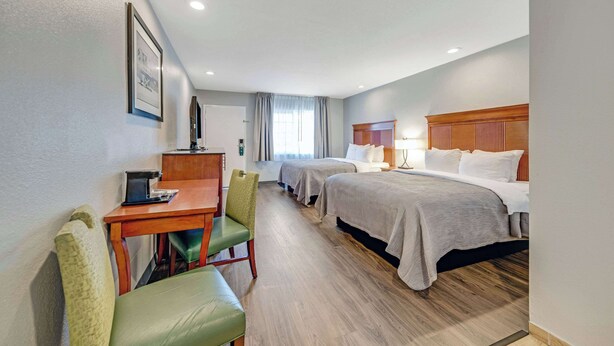 A hotel room with two beds, a desk, a chair, a desk lamp, and a framed picture on the wall. - Quality Inn Santa Cruz Downtown Area (Santa Cruz)