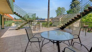 A patio area with a round table and chairs, surrounded by a green railing and a staircase. - Quality Inn Santa Cruz Downtown Area (Santa Cruz)