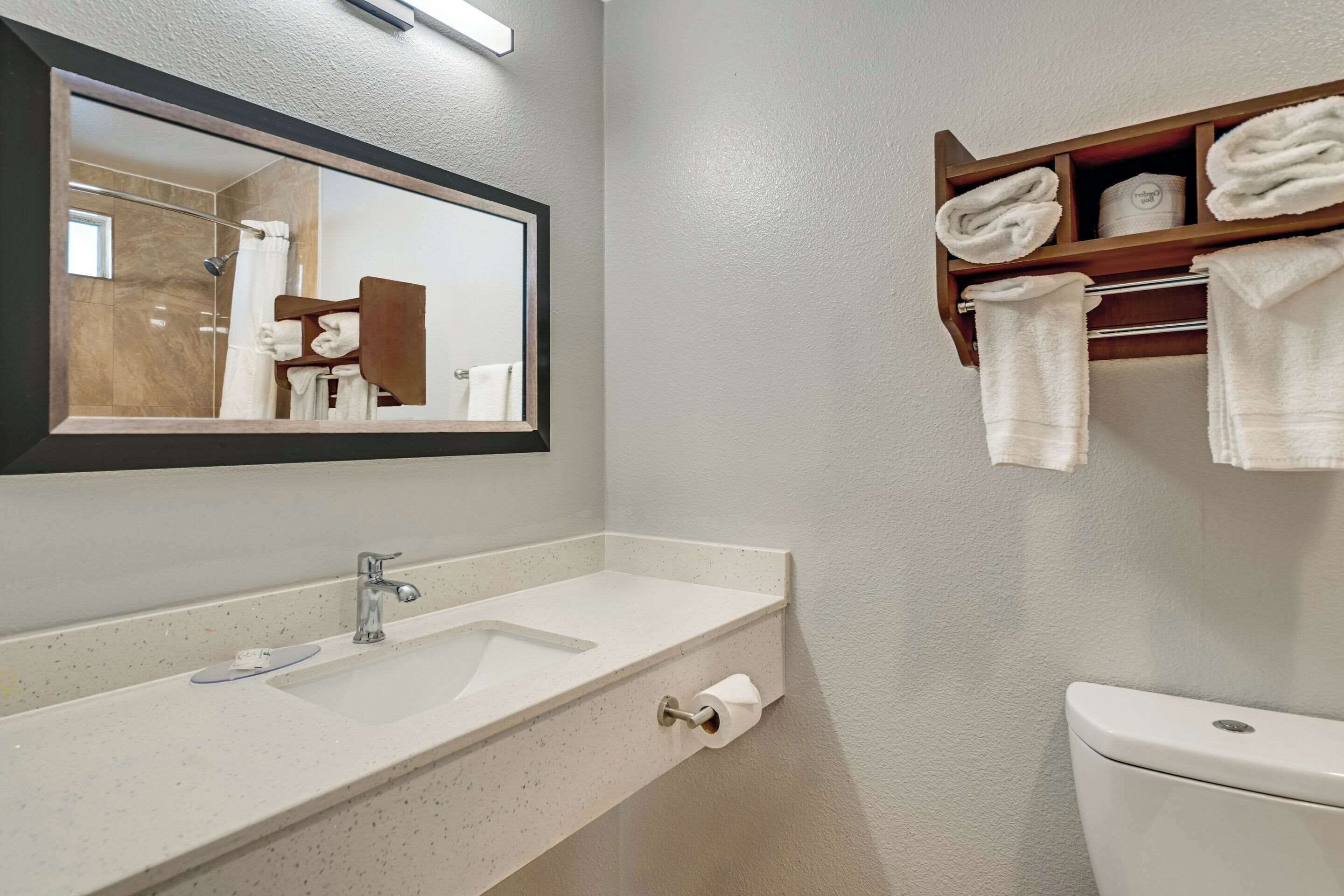 A bathroom with a sink, mirror, toilet, and towel rack.