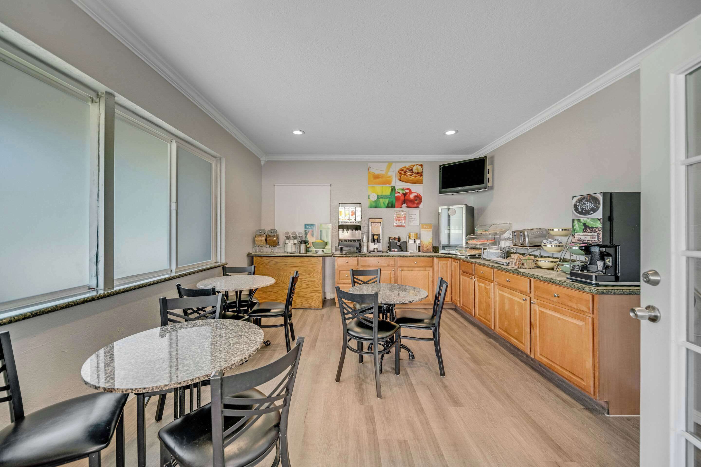 A modern kitchen with granite countertops, wooden cabinets, and a central island with seating.