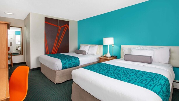 Habitació d'hotel amb dos llits, un escriptori i una cadira.