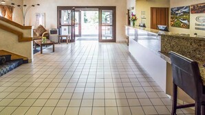 Eine Hotelhalle mit einer Rezeption, einer Treppe und einer Sitzecke.