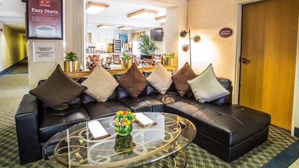 Eine Hotelhalle mit einer Ledersofa, einem Glastisch und einem Schild für das kostenlose Frühstück.