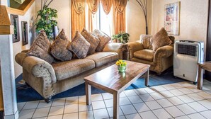 Ein Wohnzimmer mit Sofa, Sessel und Couchtisch, einer Treppe und einer Wand-Klimaanlage.