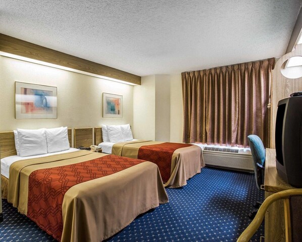 Habitación de hotel con dos camas, televisión y escritorio.
