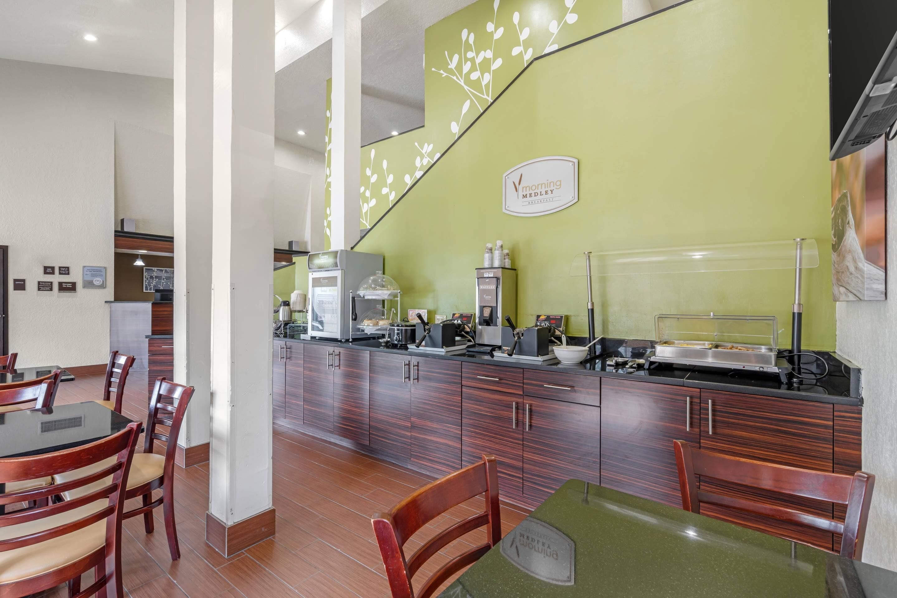 A restaurant with a green wall, wooden cabinets, and a buffet counter.