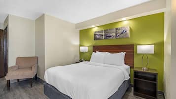 Une chambre d’hôtel avec un lit, une chaise et une table de chevet avec une lampe.